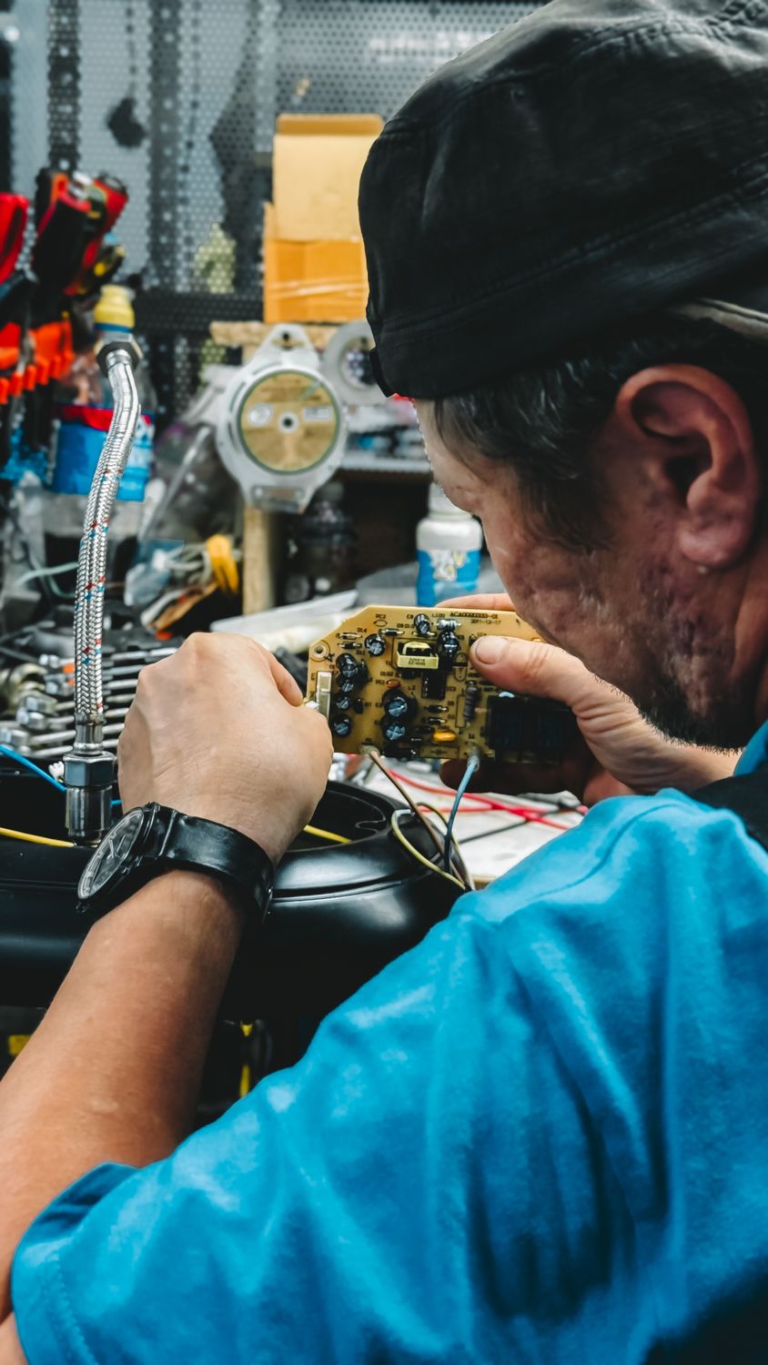 Técnico concentrado reparando uma placa eletrônica em sua oficina